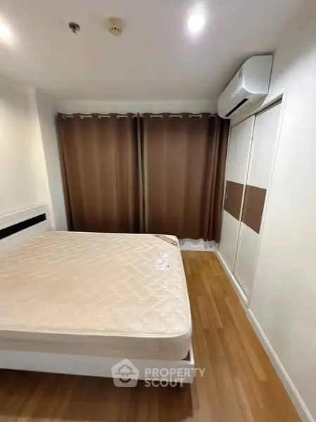 Spacious bedroom with wooden flooring and air conditioning in modern apartment.