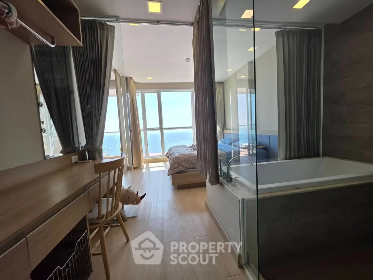Modern apartment with ocean view, featuring a cozy bedroom and luxurious bathtub.