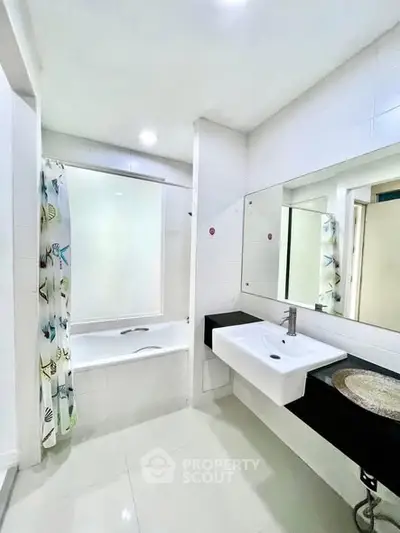 Modern bathroom with sleek fixtures and a bathtub, featuring bright lighting and elegant design.