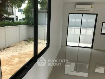 Spacious modern room with large windows and sliding glass door opening to a private yard.