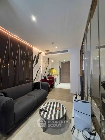 Modern living room with stylish decor and open kitchen layout, featuring a cozy sofa and elegant lighting.