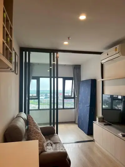 Modern living room with sliding glass doors and city view, featuring cozy sofa and air conditioning.