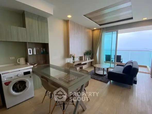 Modern living room with ocean view, featuring stylish furniture and a washing machine in a sleek open layout.