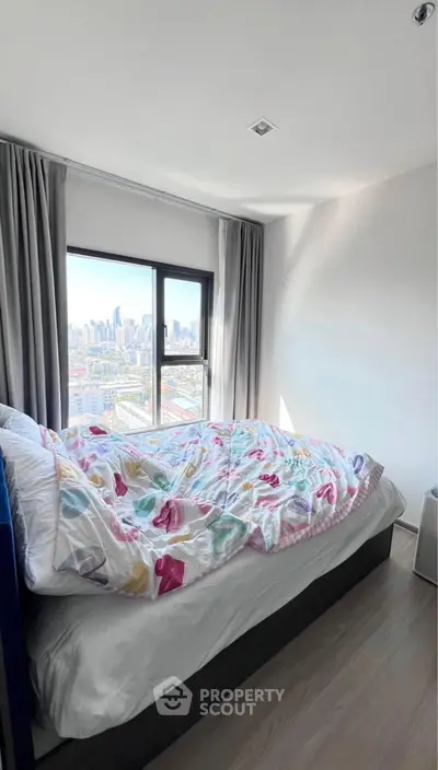Cozy bedroom with city view, featuring a comfortable bed and large window.