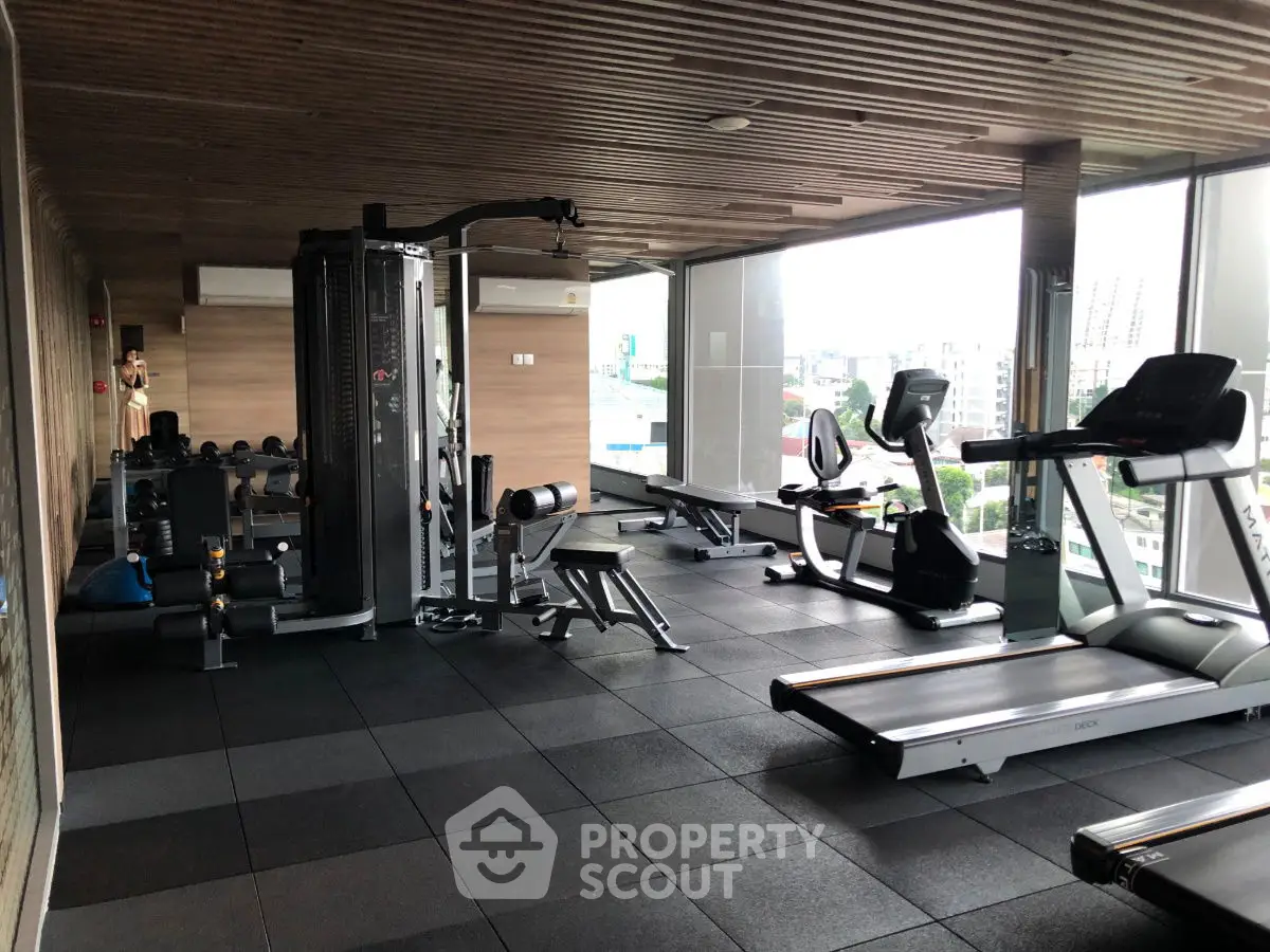 Modern gym with state-of-the-art equipment and city view in luxury apartment building.