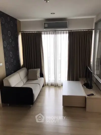 Modern living room with sleek sofa and TV, featuring floor-to-ceiling windows and stylish decor.