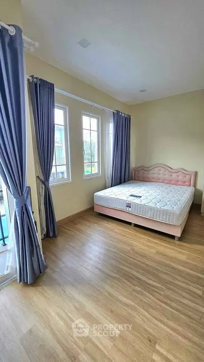 Spacious bedroom with elegant curtains and natural light, featuring a stylish bed and wooden flooring.