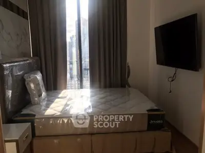 Modern bedroom with large window and wall-mounted TV in a high-rise apartment.