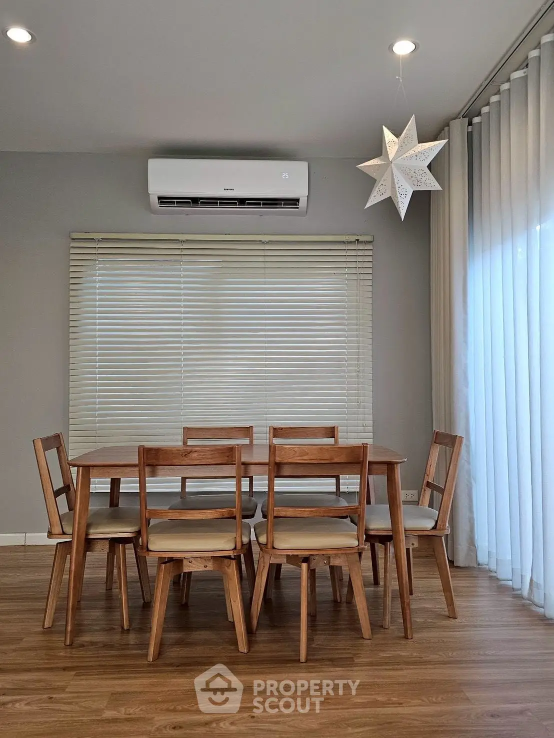 Modern dining area with wooden table and chairs, featuring air conditioning and star pendant light.
