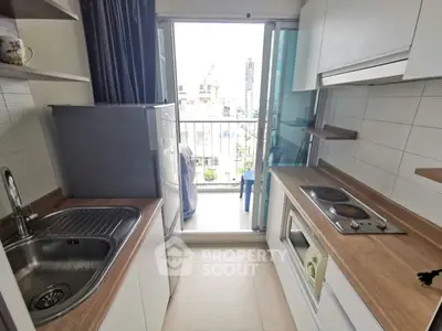 Modern kitchen with sleek design and balcony view, featuring electric stove and ample storage space.