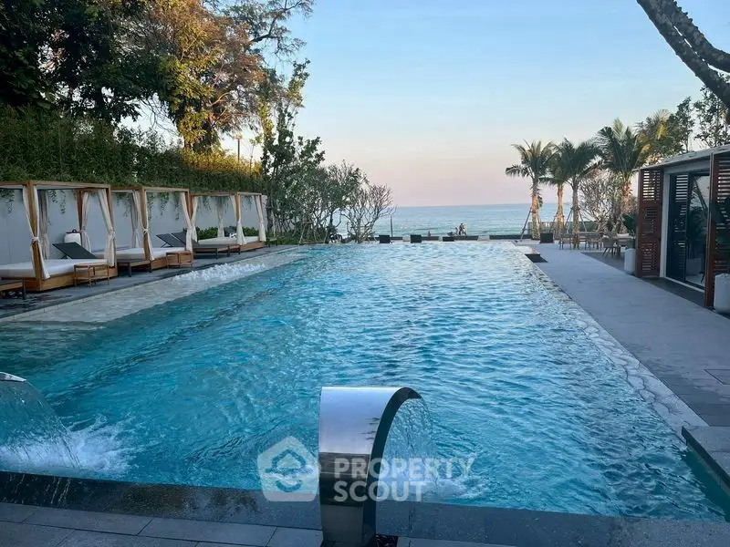 Luxurious beachfront pool with cabanas and ocean view, perfect for relaxation and leisure.
