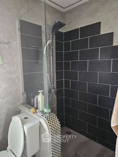 Modern bathroom with sleek black tiles and glass shower partition