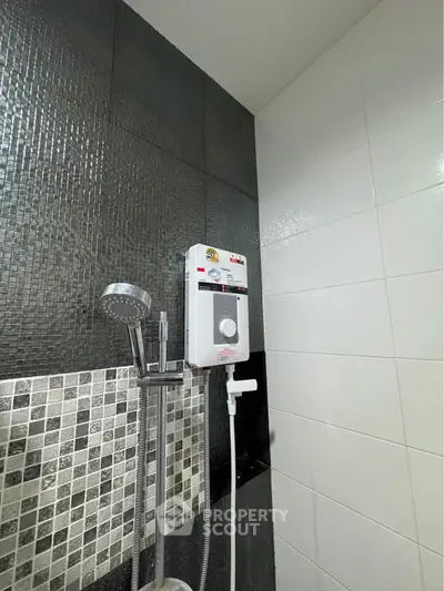 Modern bathroom with sleek shower and water heater, featuring stylish black and white tiles.