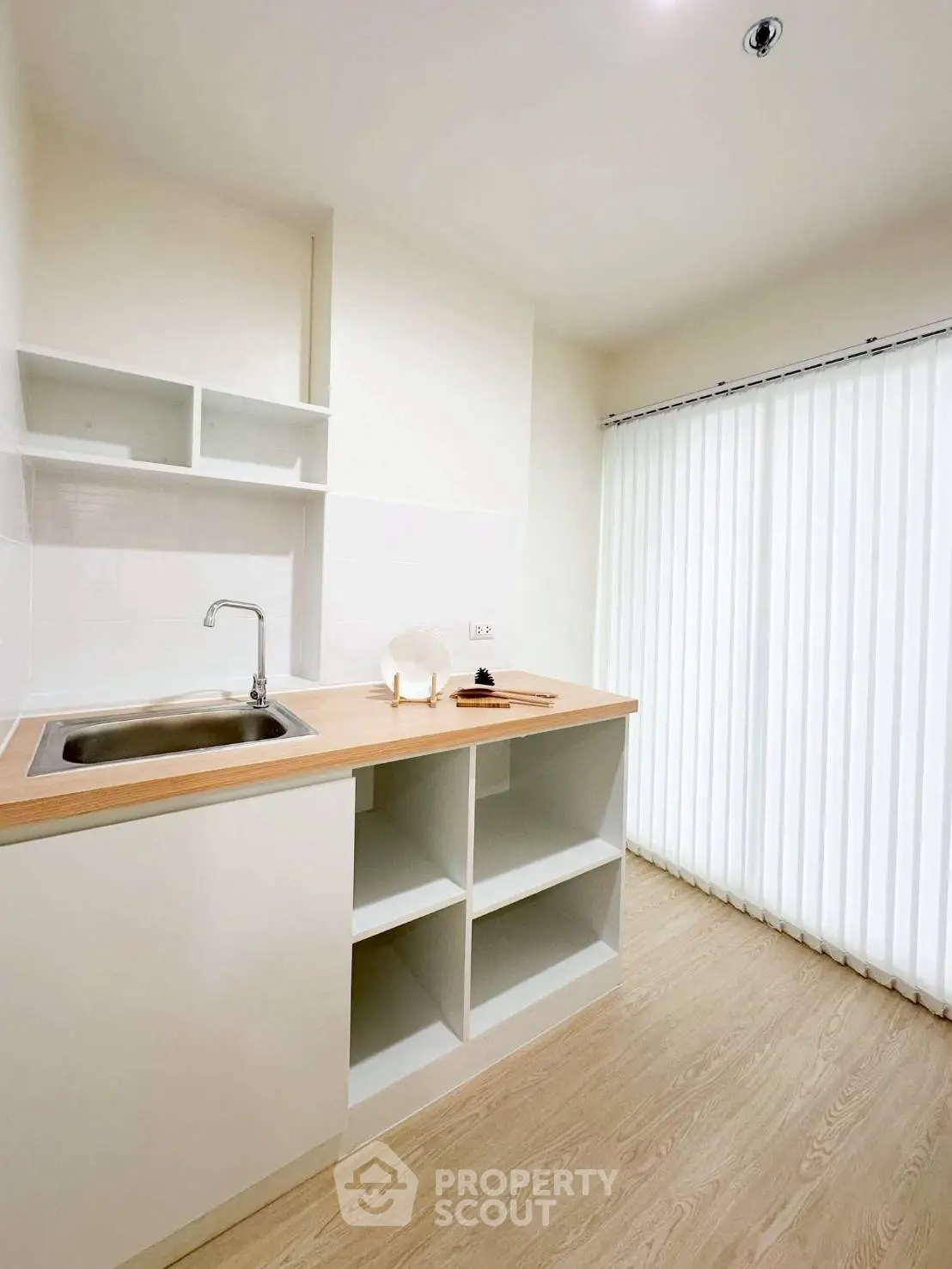 Modern minimalist kitchen with sleek white cabinets and wooden countertop.