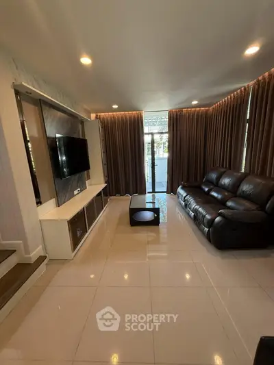 Modern living room with sleek leather sofa and wall-mounted TV, featuring elegant curtains and glossy tile flooring.