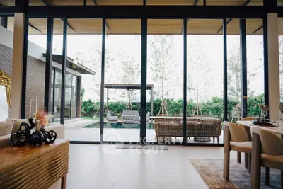 Luxurious living room with floor-to-ceiling windows overlooking a private pool and garden.