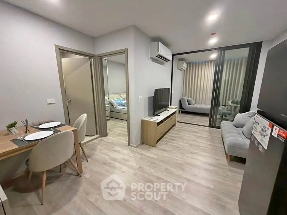 Modern open-plan living room with dining area and sleek furnishings in a stylish apartment.