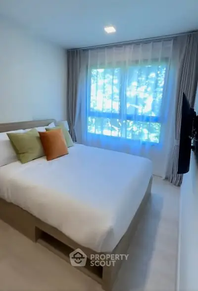 Cozy bedroom with large window and modern decor in a stylish apartment.