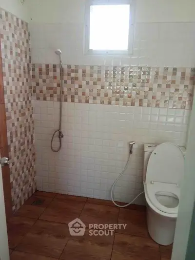 Modern bathroom with tiled walls and floor, featuring a shower and toilet.