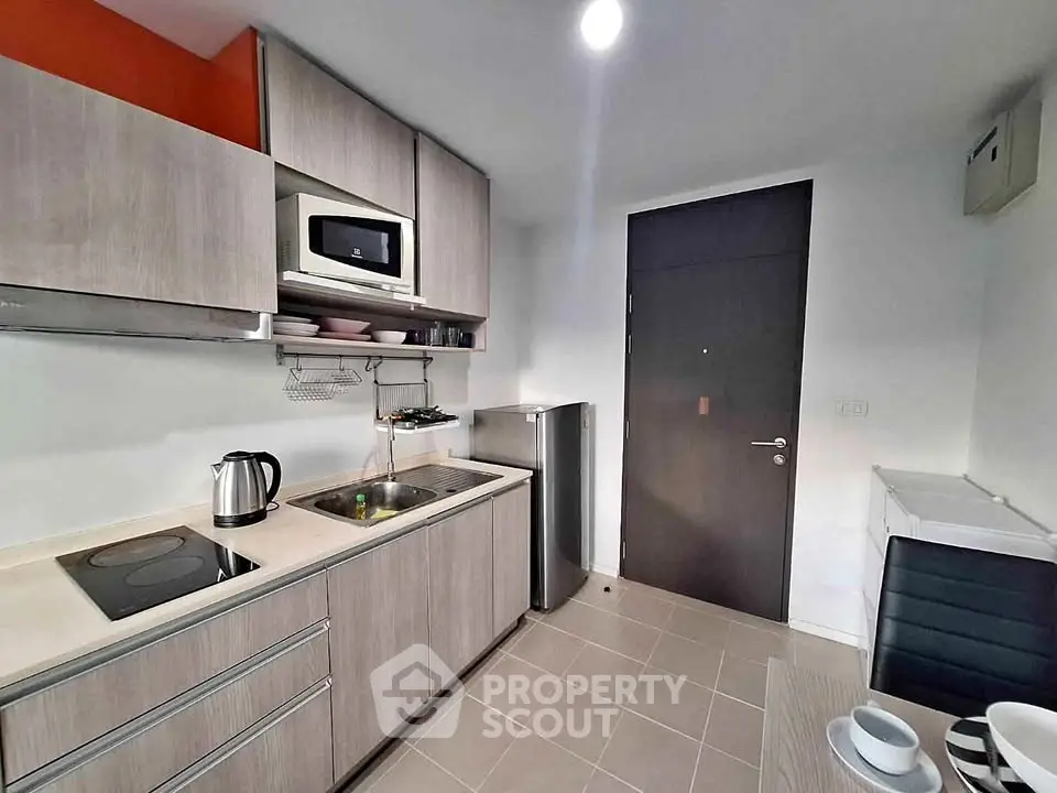Modern kitchen with sleek cabinetry, compact appliances, and dining area in stylish apartment.