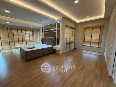 Spacious bedroom with modern design and large windows featuring wooden blinds.
