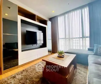 Spacious living room with modern entertainment center and large windows.
