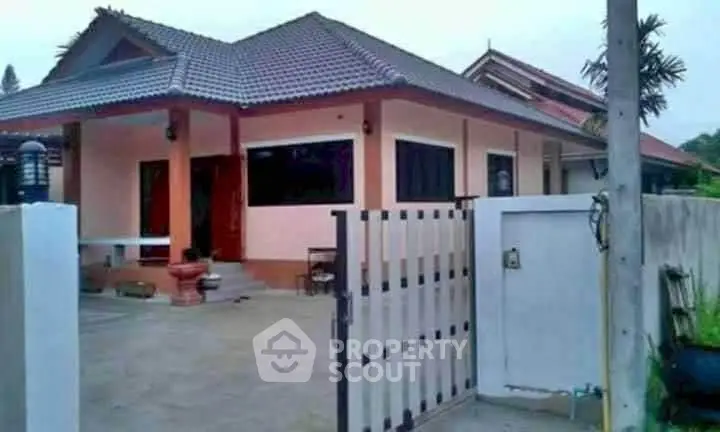 Charming single-story house with spacious driveway and modern roof design.