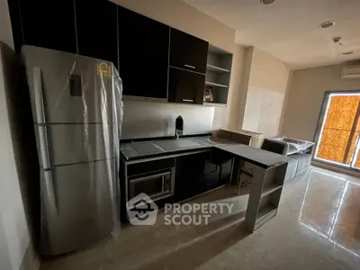 Modern kitchen with sleek black cabinets and stainless steel appliances in a cozy apartment setting.