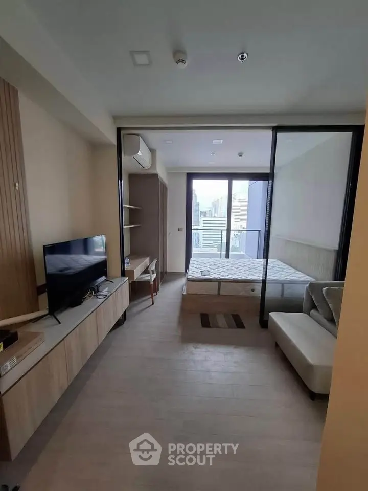 Modern studio apartment with balcony and city view, featuring sleek furniture and open layout.