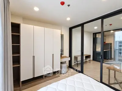 Modern bedroom with sleek wardrobe and glass sliding doors in a contemporary apartment.