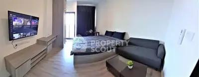 Modern studio apartment with cozy bed, sleek sofa, and wall-mounted TV, perfect for urban living.