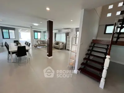 Spacious modern living room with open dining area and elegant staircase