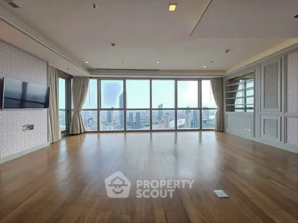 Spacious living room with panoramic city view and wooden flooring.
