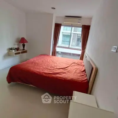 Cozy bedroom with red bedding and window view in modern apartment