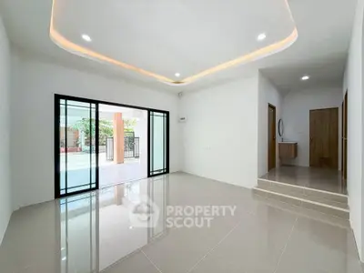 Spacious modern living room with sleek tile flooring and recessed lighting, opening to a bright outdoor area.