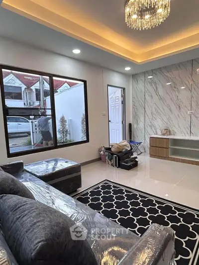 Modern living room with elegant lighting and large window, showcasing a cozy and inviting atmosphere.