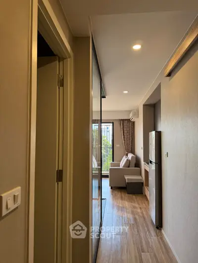 Modern apartment hallway leading to a cozy living room with natural light.