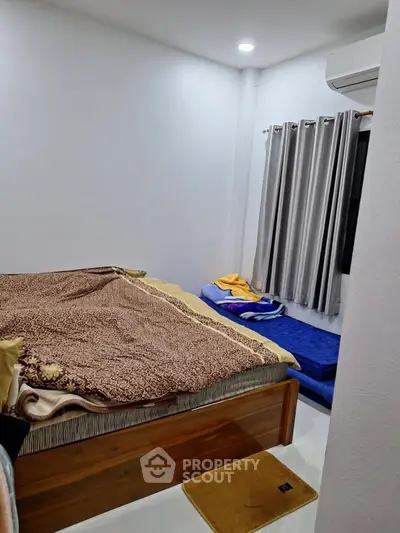 Cozy bedroom with wooden bed and air conditioning, featuring modern curtains and minimalist decor.