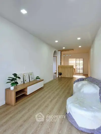 Spacious living room with modern decor and open layout, featuring wooden flooring and stylish lighting.