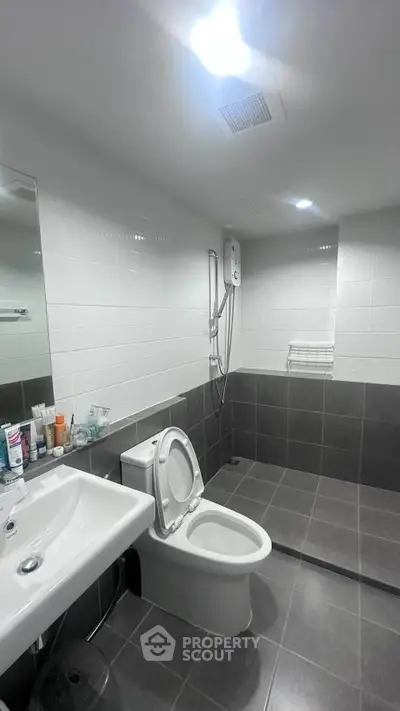 Modern bathroom with sleek fixtures and spacious shower area in contemporary apartment.