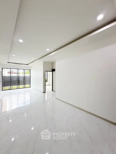 Spacious modern living room with sleek tile flooring and large windows.