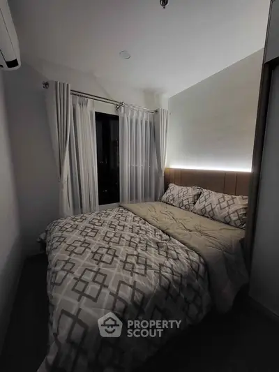 Cozy bedroom with modern decor and large window offering natural light.