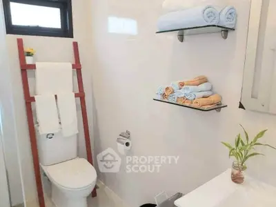 Modern bathroom with stylish ladder towel rack and elegant shelving.