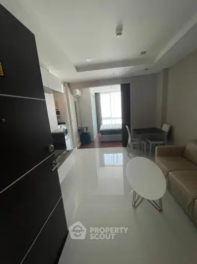 Modern apartment interior with open layout, featuring living area, dining space, and visible bedroom.