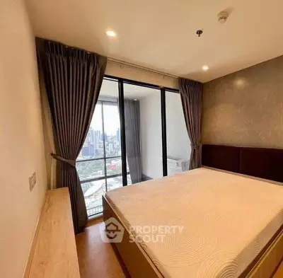 Spacious bedroom with city view and large windows in modern apartment.