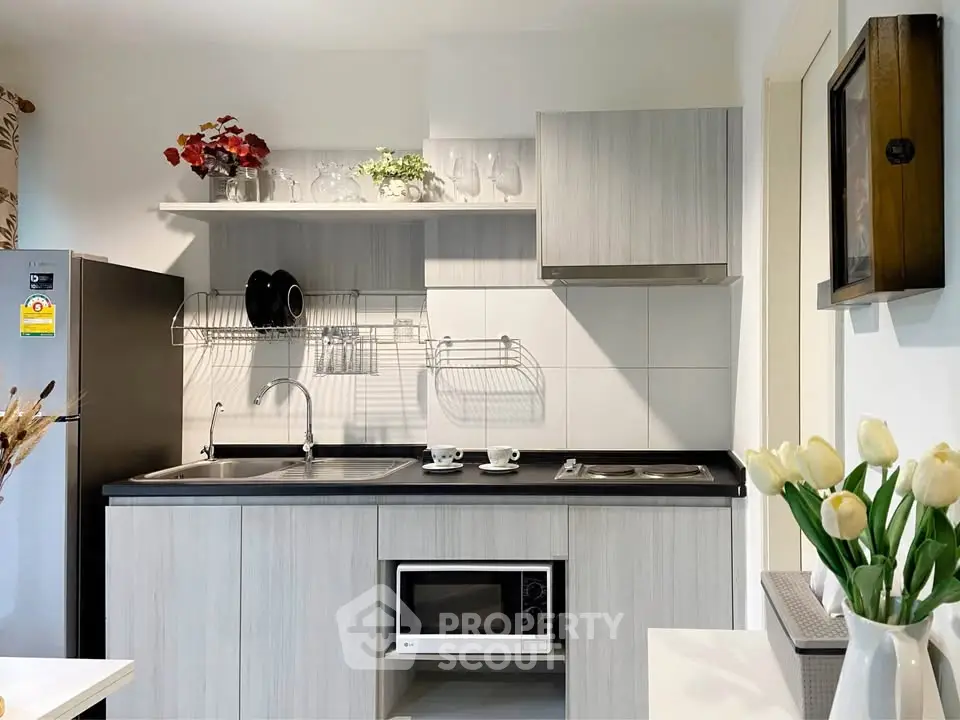 Modern kitchen with sleek cabinetry and built-in microwave, featuring elegant decor and ample storage space.