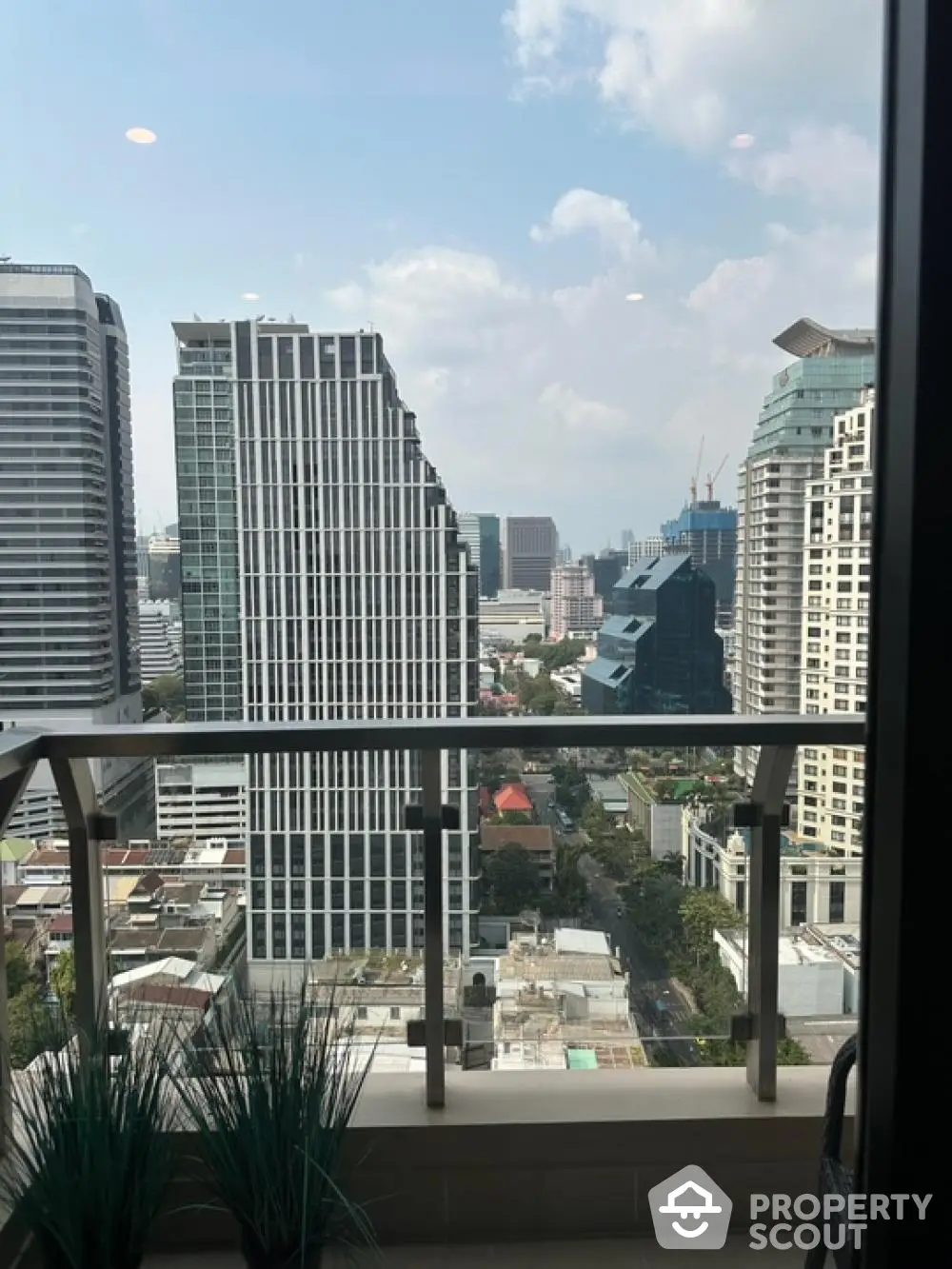 Stunning city view from modern high-rise balcony with glass railing.