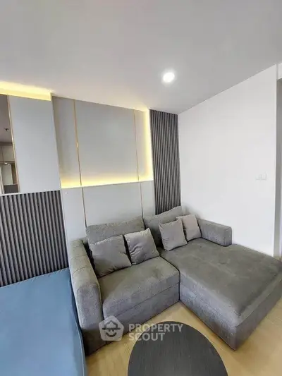 Modern living room with stylish gray sectional sofa and accent lighting
