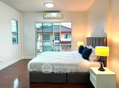 Spacious bedroom with modern decor and large windows offering natural light and neighborhood view.
