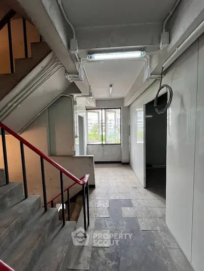 Spacious building corridor with stairway and large windows offering natural light.